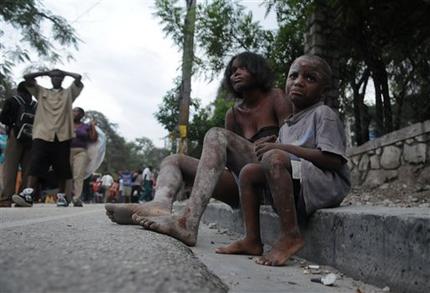 Injured people sit along a road the day after the earthquake struck Port-au-Prince, Haiti, (AP Photo/Jorge Cruz)